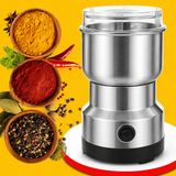 A stainless steel electric spice grinder with a clear lid and black base, shown on a bright yellow background with bowls of spices and herbs around it.